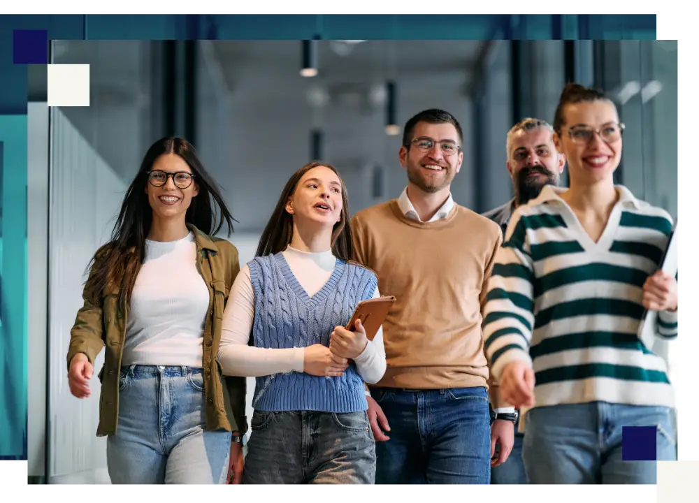 Five colleagues walking together and smiling in a bright modern office corridor